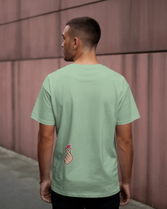 Man wearing a light green t-shirt with a design on the back against a pink wall.