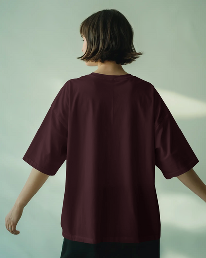 Person wearing a burgundy oversized t-shirt against a light green background